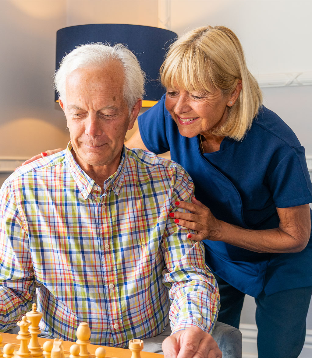 Resident plays chess alongside caring team memeber